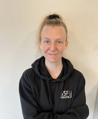 Kvinne med lyst hår og svart jakke